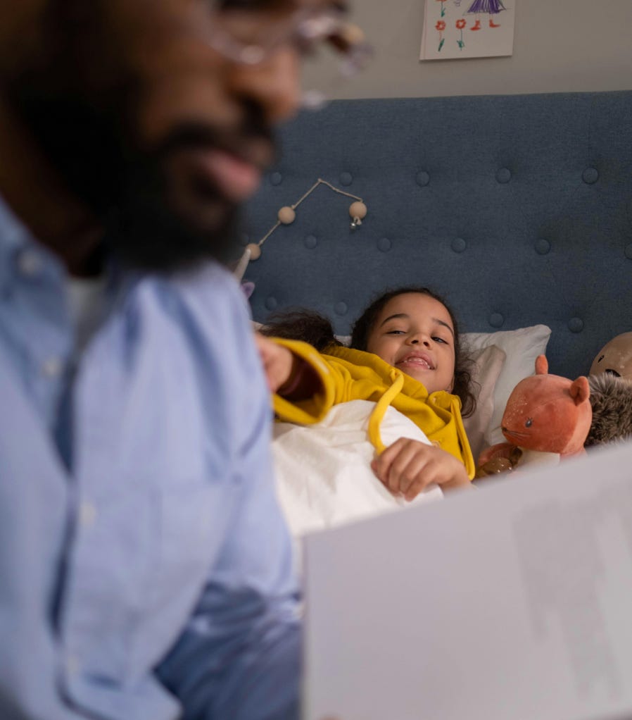 Girl Lying Down on Bed Listening to His Father Read a Book